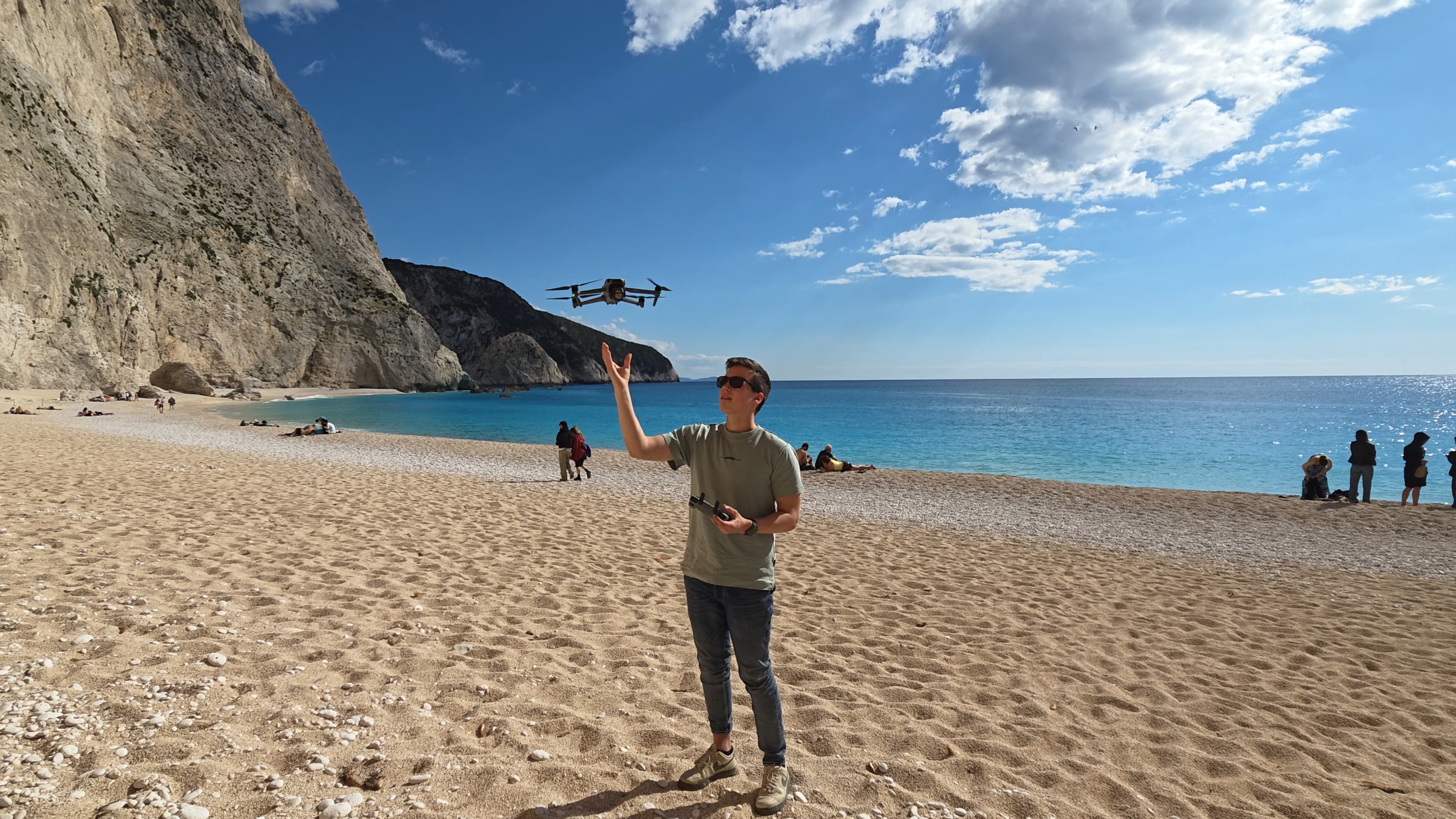 Geert Koffeman op het strand met een dronecontroller, terwijl zijn drone boven hem vliegt.