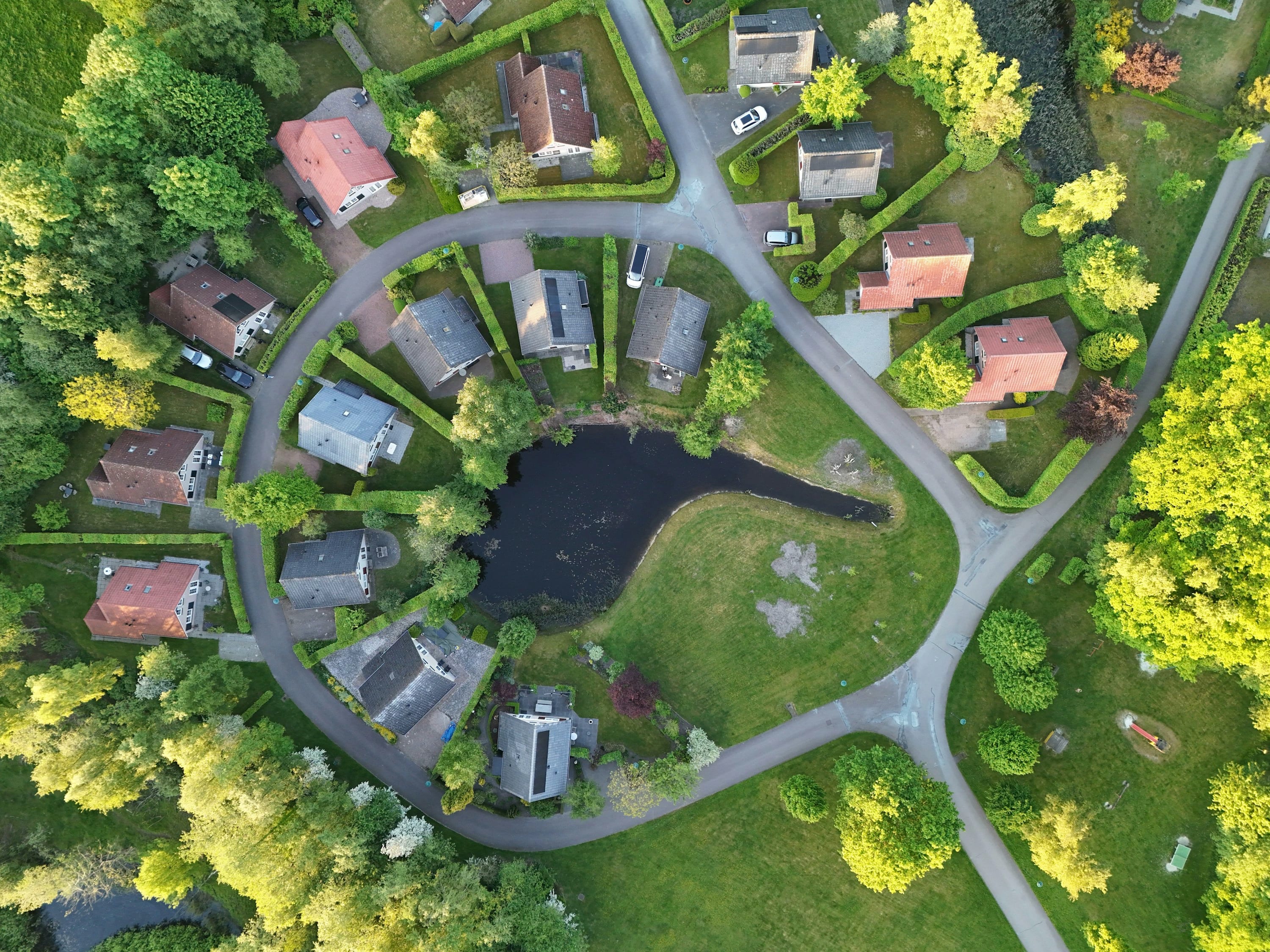 Top-down luchtfoto van Nederlandse recreatiewoningen rond groen en water in Drenthe.