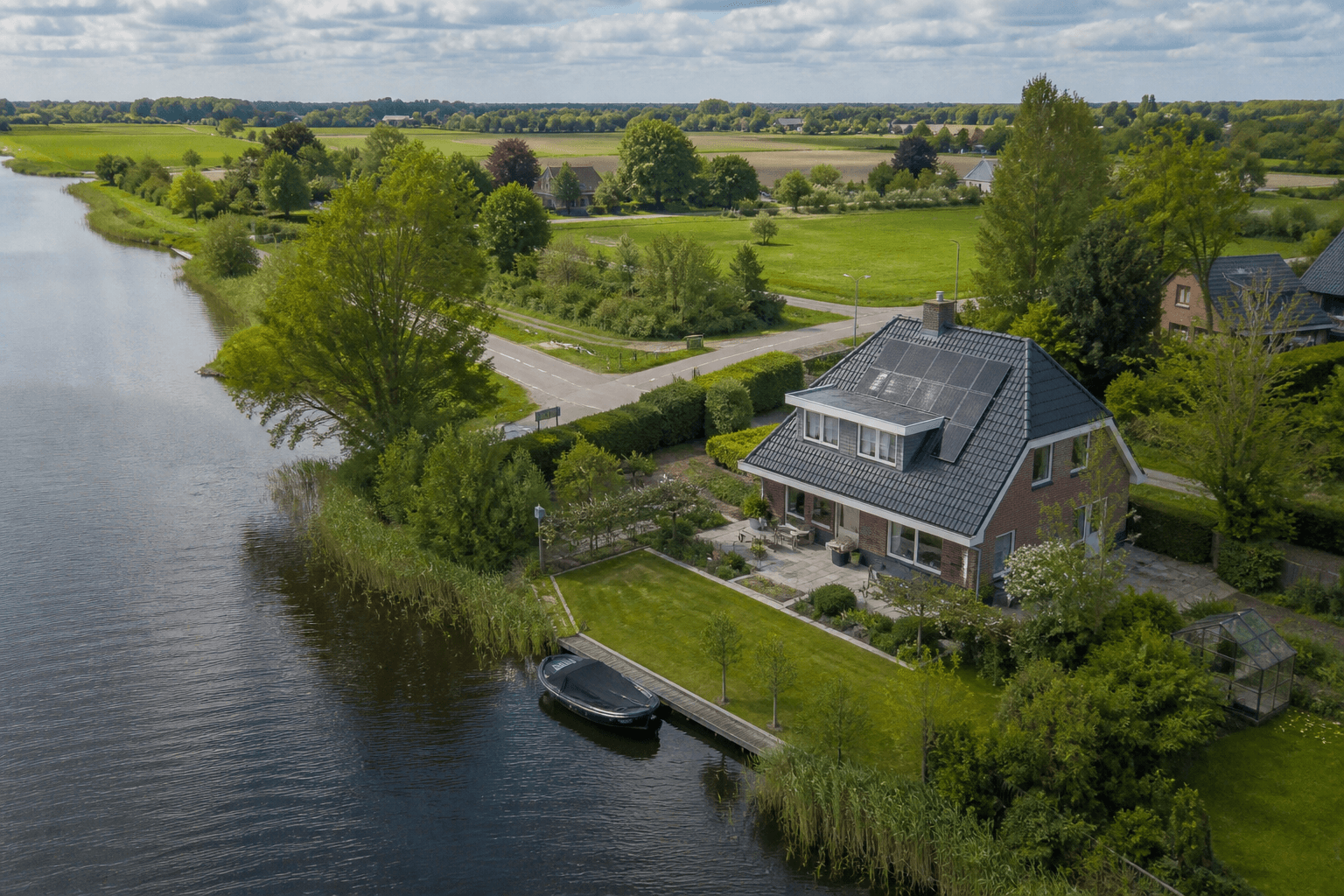 Luchtfoto van een vrijstaande woning met tuin en watergang in een Nederlands polderlandschap.