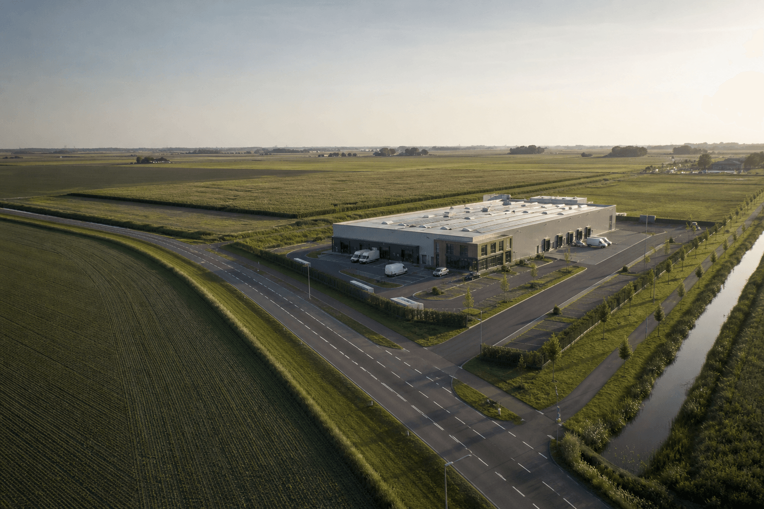 Luchtfoto van een modern bedrijfspand met polderlandschap en watergang in Flevoland.