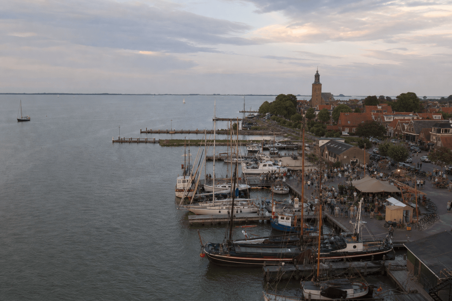 Luchtfoto van een kleinschalig evenement in een Nederlandse haven aan het water.